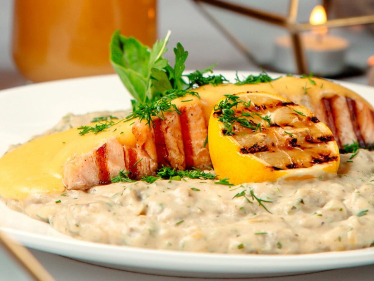 close up of grilled salmon and risotto garnished with lemon